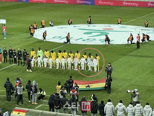 가나 수비수 알리두 세이두가 에스코트 키즈로 나선 한 어린이에게 점퍼를 덮어주고 있다.