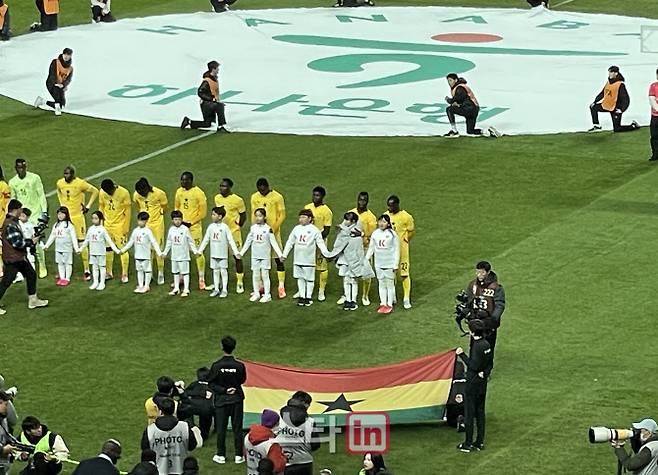 가나 수비수 알리두 세이두가 에스코트 키즈로 나선 한 어린이에게 점퍼를 덮어주고 있다.