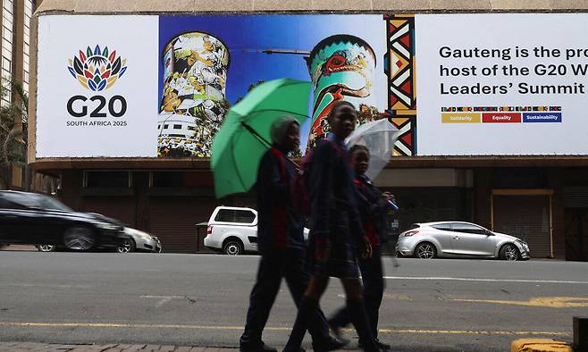 18일(현지시간) 남아프리카공화국 요하네스버그 시내의 G20 정상회의를 알리는 간판 앞을 학생들이 지나가고 있다. 로이터연합뉴스
