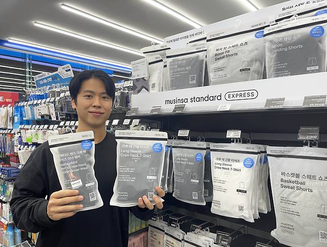 고객이 동절기를 맞아 GS25에서 새롭게 선보이는 ‘무신사 스탠다드’ 상품들을 들고 포즈를 취하고 있다. [GS리테일 제공]