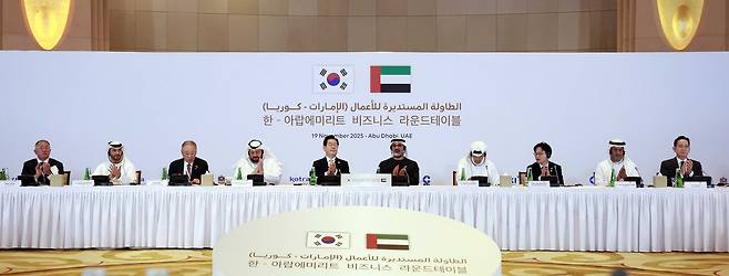 President Lee Jae Myung, center left, Crown Prince of Abu Dhabi Khaled bin Mohamed bin Zayed Al Nahyan, center right, and government officials and business leaders clap during a business roundtable at a hotel in Abu Dhabi in the United Arab Emirates (UAE), on Nov. 19. Attendees included Hyundai Motor Group Executive Chair Euisun Chung, far left, and Samsung Electronics Executive Chairman Lee Jae-yong, far right. [JOINT PRESS CORPS]