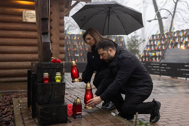 21일 젤렌스키 대통령과 부인 올레나 젤렌스카가 수도 키이우의 ‘천국에 있는 100인의 영웅 거리’에서 2004년의 오렌지 혁명, 2013년의 유로마이단 민주화 혁명에서 숨진 시위대원들을 추모하는 촛불을 켜고 있다./AFP 연합뉴스