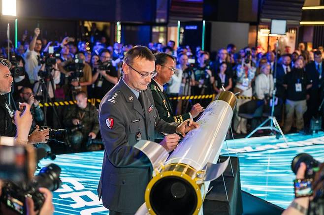 폴란드 키엘체 국제 방위산업 전시회(MSPO 2025)에서 지난 9월 열린 '천무 유도탄 생산을 위한 현지 합작법인 계약식'에서 한국과 폴란드 양국 정부·군·업계 관계자들이 성공적인 방산협력을 축하하며 천무 모형탄에 서명하고 있다. 한화에어로스페이스 제공