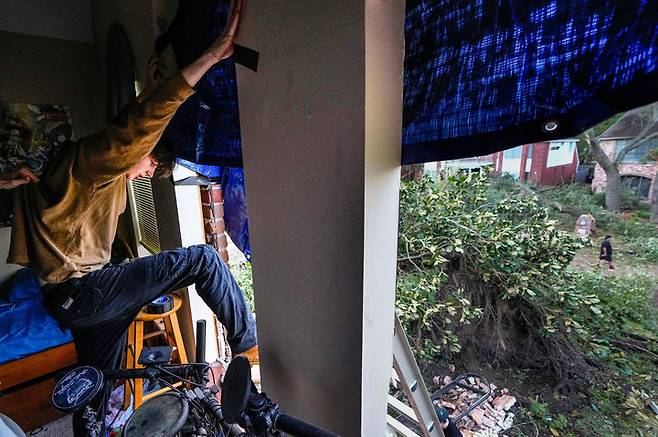 [텍사스주=AP/뉴시스] 24일(현지 시간) 미국 텍사스주 메모리얼 노스웨스트 지역에서 주민들이 토네이도로 인해 파손된 주택 창문에 방수포를 설치하고 있다. 2025.11.25.