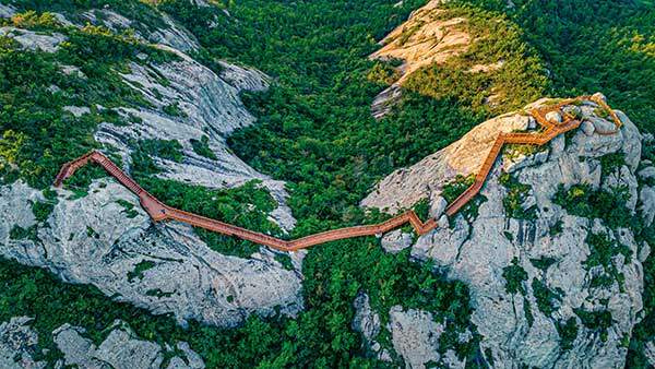 그림산 능선에서 투구봉으로 이어지는 붉은 데크길이 푸른 자연과 대비되어 하나의 작품처럼 보인다.