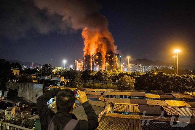 원경으로 본 왕 푹 코트 아파트 화재 현장, 한 시민이 화재 현장을 카메라에 담고 있다. ⓒ AFP=뉴스1 ⓒ News1 박형기 기자