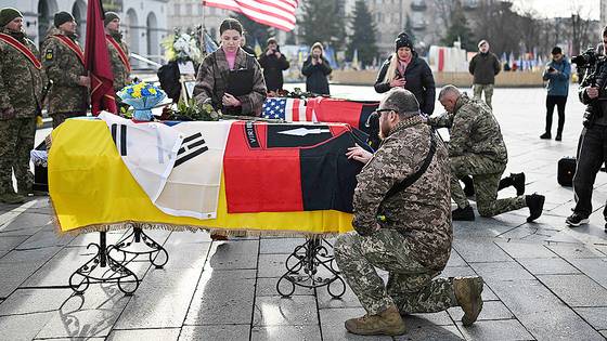 지난 25일 우크라이나 수도 키이우에서 전사한 한국인 의용군의 관을 앞에 두고 우크라이나 군인이 애도하고 있다. AFP=연합뉴스