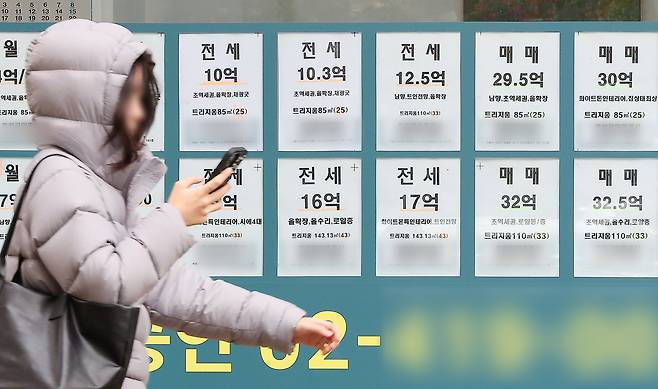 A person passes by a real estate agency with listings for nearby apartments in Seoul on Nov. 24. [NEWS1]
