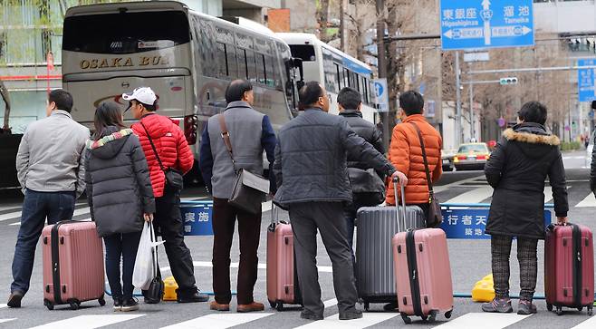 Chinese tourists wait for a bus in Tokyo's Ginza shopping district in Tokyo on March 12, 2016. [AP/YONHAP]