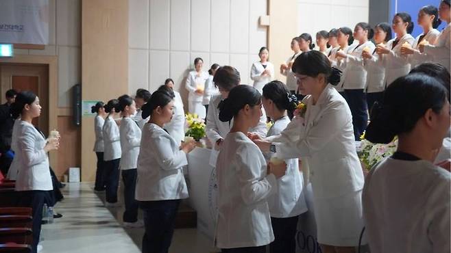[서울=뉴시스] 삼육보건대 제76회 나이팅게일 선서식에서 학생 대표와 교수진이 촛불점화를 진행하고 있다. (사진=삼육보건대 제공) 2025.11.27. photo@newsis.com *재판매 및 DB 금지