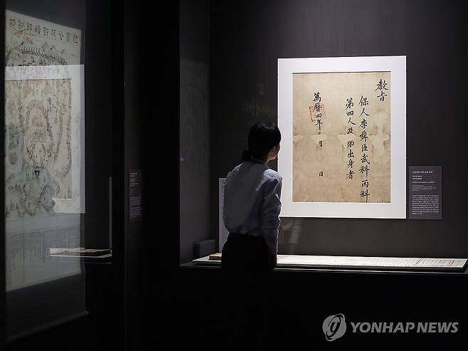 이순신의 무과 급제 교지 (서울=연합뉴스) 강민지 기자 = 27일 서울 용산구 국립중앙박물관에서 열린 '우리들의 이순신' 전시 언론공개회에서 참석자가 '무과 급제 교지'를 둘러보고 있다. 충무공 탄신 480주년과 광복 80주년을 맞아 선보이는 전시는 다음 달 4일까지는 무료 개방한다. 2025.11.27  mjkang@yna.co.kr