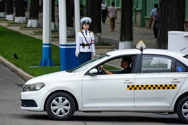 A taxi car passes a traffic guard in downtown Pyongyang, North Korea, on June 30. [TASS/YONHAP]