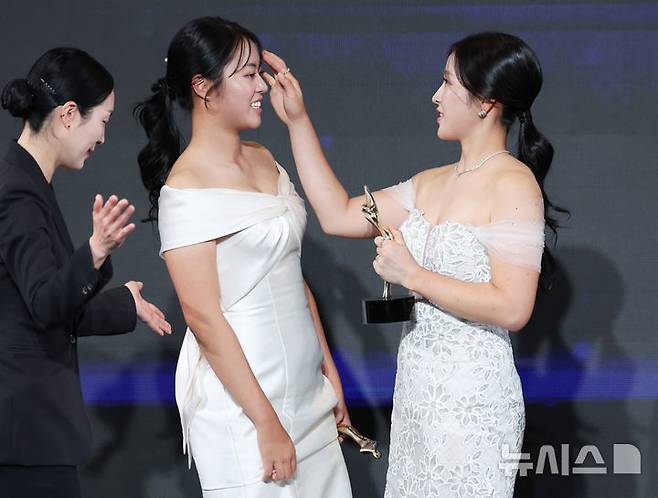 [서울=뉴시스] 김진아 기자 = 28일 서울 강남구 그랜드 인터컨티넨탈 서울 파르나스에서 열린 '2025 KLPGA 대상 시상식'에서 위메이드 대상을 수상한 유현조가 신인상을 수상한 서교림의 머리를 정리해주고 있다. 2025.11.28. bluesoda@newsis.com