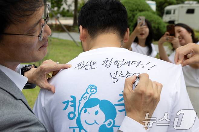 박주민 국회 보건복지위원장이 지난 8월 27일 서울 여의도 국회 소통관 앞에서 열린 '문신사법 의결 경축' 타투이스트들의 캐리커쳐 행사에 참석한 뒤 타투이스트의 티셔츠에 사인을 해주고 있다. (사진은 기사 내용과 무관함) 2025.8.27/뉴스1 ⓒ News1 이승배 기자