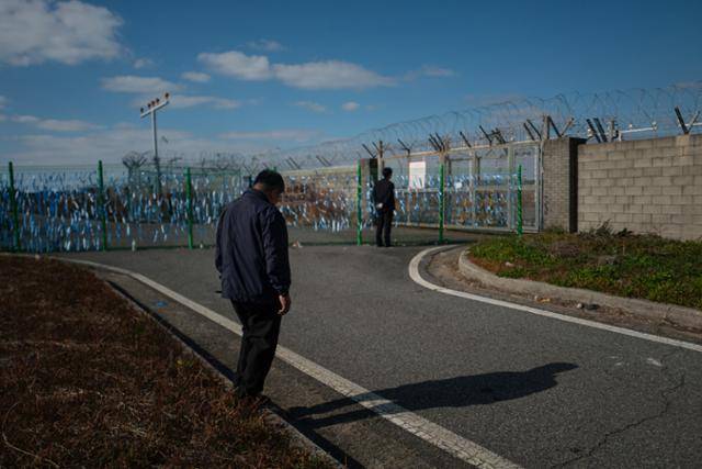 박인욱(70)씨가 26일 전남 무안국제공항 참사 현장 인근 추모 리본이 매달린 울타리 곁을 서성이고 있다. 박씨는 지난 참사로 아내와 딸, 사위 그리고 두 손주를 잃었다. 무안=하상윤 기자