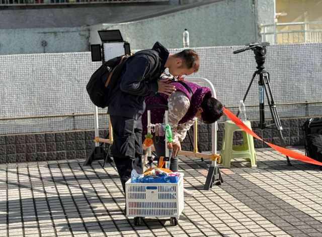 29일 홍콩 타이포구 고층 아파트 단지 '웡 푹 코트' 인근 '광 푹 시장' 광장에서 안나 탕이 화재 현장을 향해 허리를 굽혀 기도하고 있다. 옆에는 그와 지인이 가져온 이재민들을 위한 물품이 담긴 장바구니 가방이 놓여 있다. 홍콩=허유정 기자