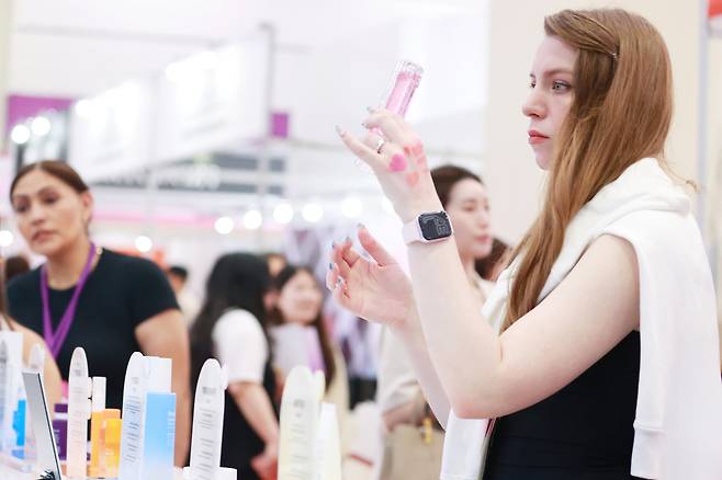 A foreign buyer examines products at the 2025 Seoul International Cosmetics & Beauty Industry Expo and International Health Industry Expo at Coex in Gangnam District, southern Seoul, in May. [YONHAP]