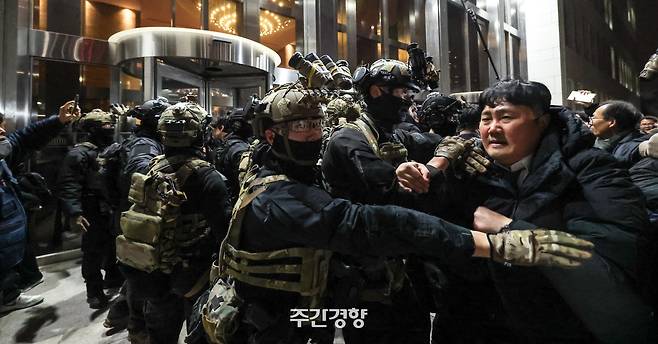 윤석열 대통령이 비상계엄을 선포한 후 자정을 넘긴 지난해 12월 4일 새벽 국회의사당에 도착한 무장군인들이 국회 본청 진입을 시도하자 국회 직원 등이 격렬히 막아서고 있다. 성동훈 기자