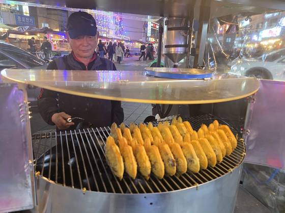 A man grills bungeoppang at a stall in Jongno District, central Seoul. [JOONGANG ILBO]