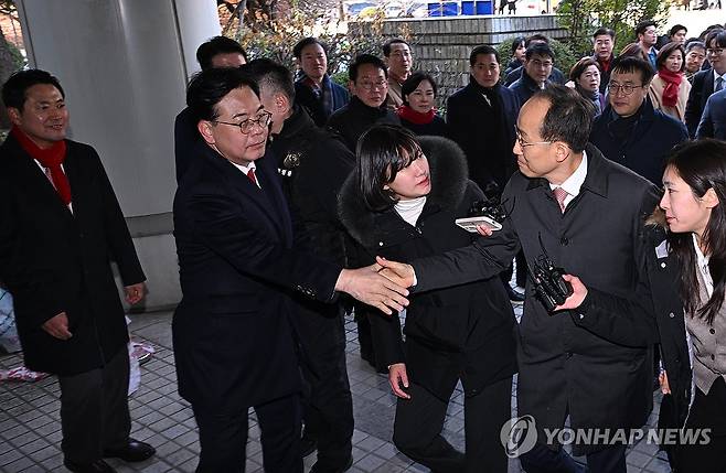 송언석 원내대표와 악수하는 추경호 의원 (서울=연합뉴스) 최재구 기자 = 국민의힘 추경호 의원이 2일 서울 서초구 서울중앙지방법원에서 열린 구속 전 피의자 심문(영장실질심사)에 출석, 송언석 원내대표와 악수하고 있다. 
    추 의원은 12·3 비상계엄 당시 국민의힘 원내대표 지위를 이용해 의원들의 계엄 해제 표결 참여를 방해한 혐의를 받는다. 2025.12.2 [공동취재] jjaeck9@yna.co.kr