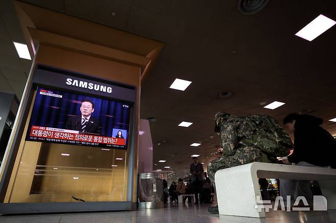 [서울=뉴시스] 정병혁 기자 = 12·3 비상계엄 1년을 맞은 3일 서울 중구 서울역 대합실에서 시민들이 이재명 대통령의 대국민 특별성명 발표를 TV를 통해 지켜보고 있다. 2025.12.03. jhope@newsis.com