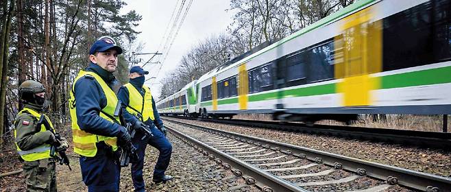 AFP 연합뉴스러 배후 의심… 철도 파괴후 보안 강화한 폴란드 지난달 27일 폴란드 수도 바르샤바 외곽을 달리는 열차를 철도 보안 요원 두 명과 무장한 국토방위군이 바라보고 있다. 폴란드는 지난달 철도 파괴와 화재 등 사건 배후에 러시아가 있다고 보고 있다.