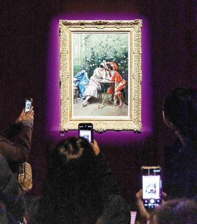 3일 서울 용산 국립중앙박물관 전시장에서 관람객들이 스페인 화가 라이문도 데 마드라소 이 가레타의 유화 ‘가면무도회 참가자들’을 휴대폰에 담고 있다. 가장무도회에 참가한 남녀가 햇빛 비치는 온실에서 잠시 둘만의 시간을 즐기는 모습을 묘사한 그림이다. 101.6×64.8cm. /김지호 기자