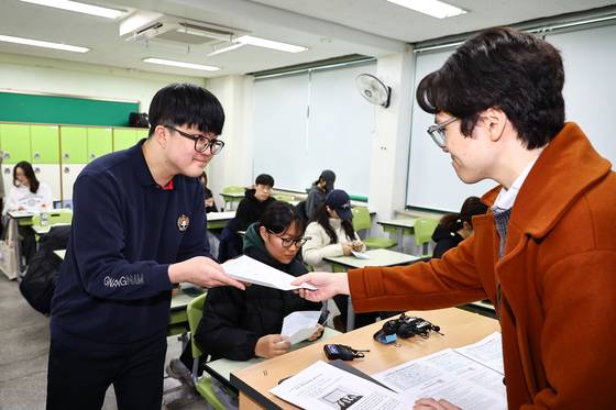 2025학년도 대학수학능력시험 성적표가 배부된 5일 오전 서울 광진구 광남고에서 수능 만점을 받은 왕정건 군이 고무성 담임 교사로부터 수능 성적표를 받고 있다. 김종호 기자