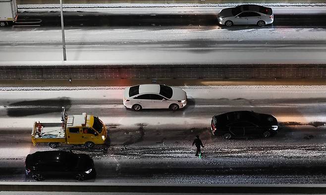 4일 서울 서대문구 홍제동 내부순환로에서 차량이 얼어붙은 눈길에 서행하는 가운데 내부순환로에서 시설관리공단 관계자가 제설 작업을 하고 있다. 연합뉴스