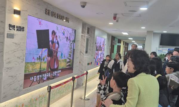 한백초 학교 관계자들과 학생들이 학교에 설치된 ‘디지털 갤러리’를 바라보고 있다. /한백초 제공