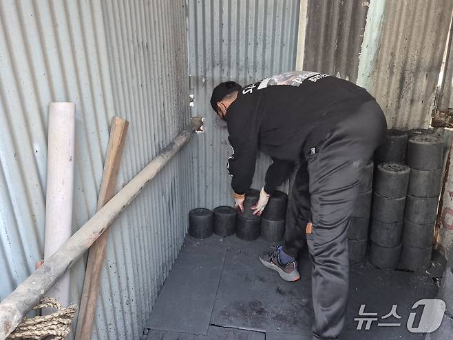 열린마음봉사단이 7일 울산 남구 선암동의 한 마을에서 에너지취약 계층의 창고에 연탄을 쌓고 있다.202512.8/뉴스1ⓒ 뉴스1 박정현 기자