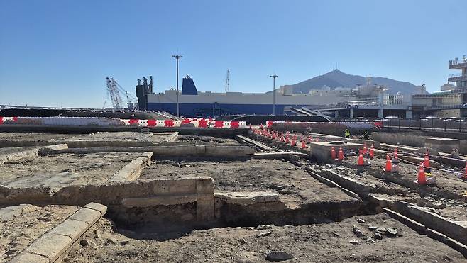 부산항 1부두 서쪽 옛 국제여객터미널 터의 발굴 조사 현장을 찍은 사진. 1910~1920년대 일제가 설치한 철도 역사의 기초 부분과 철도의 침목, 플랫폼 기단부 등이 보인다. 남쪽 부두 뒤에 대형 화물선이 정박한 가운데 발굴 현장이 펼쳐진 색다른 광경을 보여준다. 건축사학계 관계자 제공