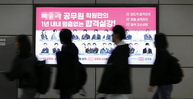 공무원 시험 수험생들이 서울 노량진역에 위치한 공무원 학원 광고판 앞을 지나가고 있다. 올해 국가공무원 9급 공채 선발시험 평균 경쟁률은 24.3대 1로 9년 만에 반등했다. ⓒ연합뉴스
