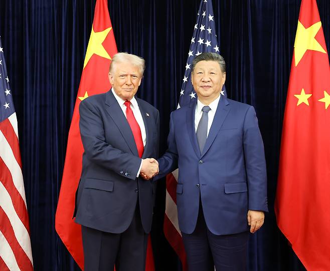 US President Donald Trump (left) and Chinese President Xi Jinping shake hands upon their meeting in Busan, Oct. 30. (Yonhap)