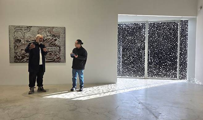 [사진=박현주 미술전문기자] 9일 서울 국제갤러리 K3 전시장에서 다니엘 보이드가 자신의 신작 앞에서 작업 방식을 설명하고 있다.작품 뒤편의 점무늬 패널을 통과한 햇빛이 바닥 위로 흘러들며, 보이드 특유의 ‘점 우주’를 전시장 전체로 확장시킨다. 2025.12.09. hyun@newsis.com *재판매 및 DB 금지