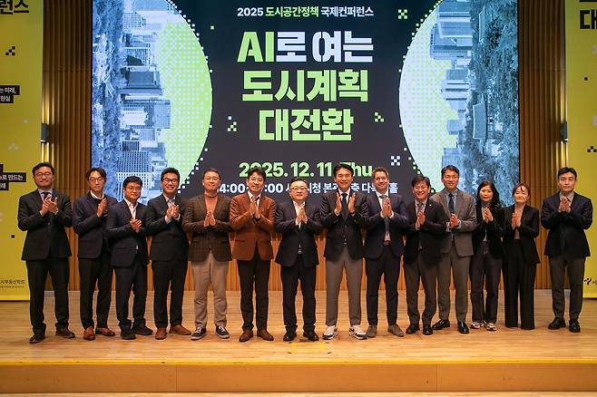 Speakers and participants clap during a group photo session at the “AI and the Great Transformation of Urban Planning” conference at City Hall in central Seoul on Dec. 11. [SEOUL METROPOLITAN GOVERNMENT]
