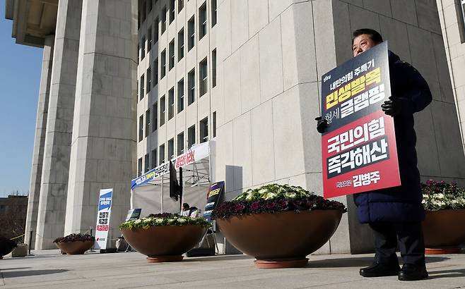 ▲ 더불어민주당 김병주 최고위원이 12일 국회 본청 앞에서 '8대 악법 저지'를 내세워 천막 농성을 이어가는 국민의힘 농성장 옆에서 내란 청산과 국민의힘 해산을 촉구하며 1인 시위를 하고 있다. /연합뉴스
