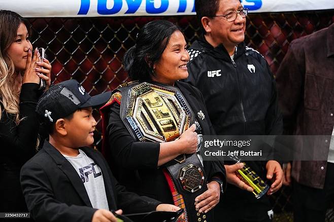 조슈아 반의 어머니(오른쪽 둘째)가 UFC 챔피언 벨트를 어깨에 걸고 아들의 승리 소감을 듣고 있다./게티이미지코리아