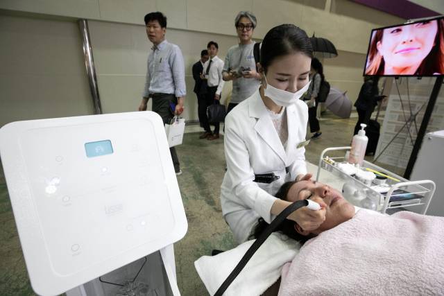 서울 강남구에서 열린 '서울국제화장품·미용산업박람회'에서 한 외국인 관람객이 기기 체험을 하고 있다. 뉴스1
