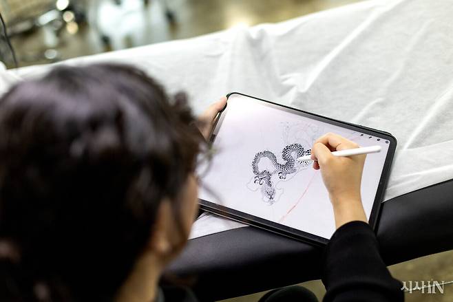 황도씨가 태블릿 PC로 타투 도안을 그리고 있다. 그는 아주 가는 선으로 이루어진 섬세하고 정교한 스타일의 타투를 하는 ‘파인라인 타투이스트’다. ⓒ시사IN 신선영