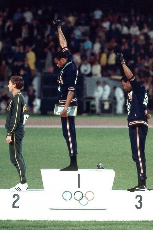 멕시코시티 올림픽 메달 수상대에서 검은 장갑을 낀 주먹을 들어 올린 토미 스미스(가운데)와 존 카를로스(오른쪽). 검은 양말을 신고 푸마 신발을 옆에 벗어둔 것도 역시 인종차별에 대한 항의 표시다.