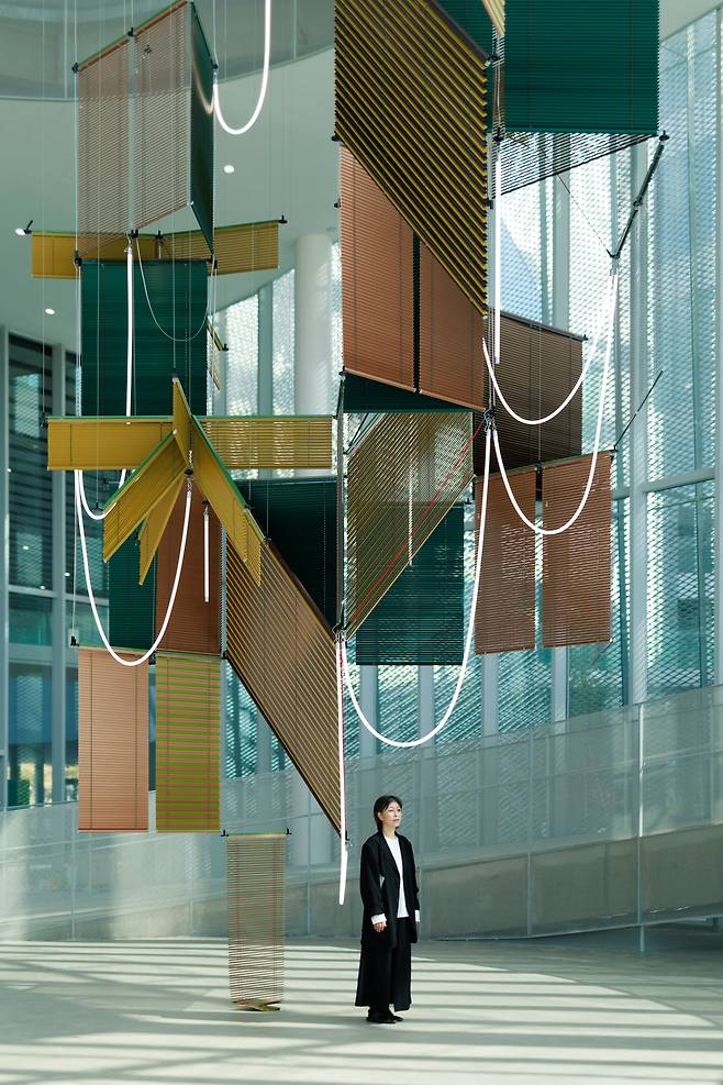 13일 개관한 대만 타이중미술관에 전시된 ‘유동 봉헌–삼합 나무 그늘(Liquid Votive–Tree Shade Triad)’ 아래 작가 양혜규가 서 있다./국제갤러리