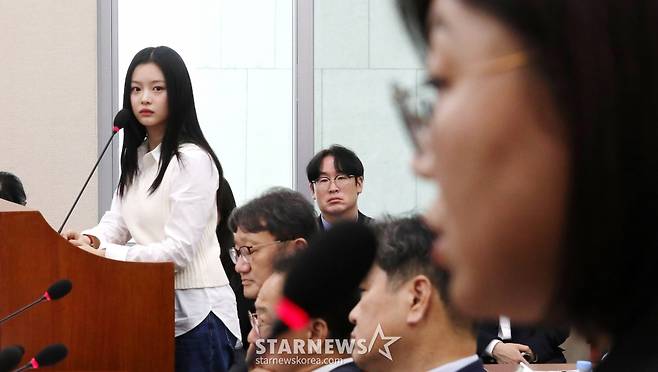 [서울=뉴시스] 국회사진기자단 = 그룹 뉴진스 멤버 하니가 15일 오후 서울 여의도 국회에서 열린 환경노동위원회의 경제사회노동위원회, 중앙노동위원회, 최저임금위원회 등에 대한 국정감사에 참고인 자격으로 출석해 김주영 어도어 대표이사 겸 하이브 최고인사책임자를 응시하고 있다. 2024.10.15. photo@newsis.com /사진=