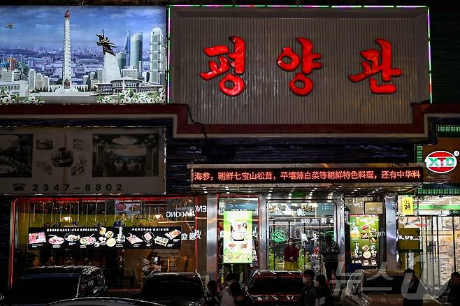 2023년 3월 31일 중국 북동부 랴오닝성 선양의 한 북한 마을에 있는 북한 식당 입구에 마스크를 쓴 북한 노동자가 서 있다. 2023.03.31. ⓒ AFP=뉴스1 ⓒ News1 이정환 기자