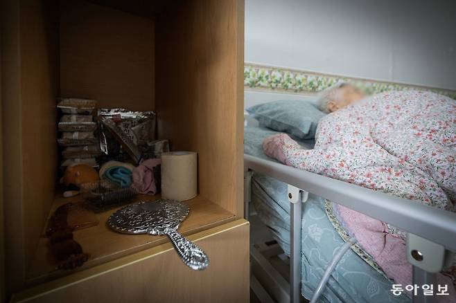 전동침대에 누워 자는 옥분의 옆으로 은색 손거울이 엎어져 있다.