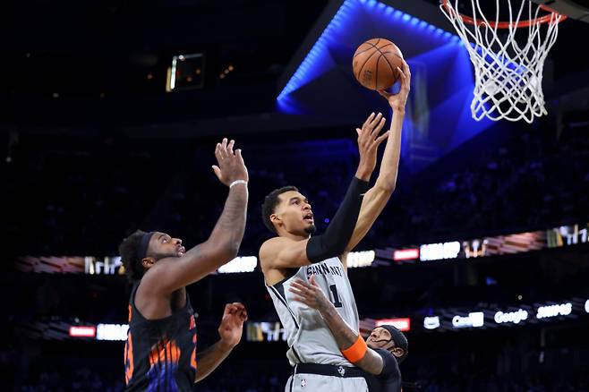 <yonhap photo-3016=""> San Antonio Spurs forward Victor Wembanyama (1) shoots against New York Knicks center Mitchell Robinson (23) and guard Jordan Clarkson (00) during the first half of the NBA Cup championship basketball game Tuesday, Dec. 16, 2025, in Las Vegas. (AP Photo/Ian Maule)/2025-12-17 12:05:51/ <저작권자 ⓒ 1980-2025 ㈜연합뉴스. 무단 전재 재배포 금지, AI 학습 및 활용 금지></yonhap>