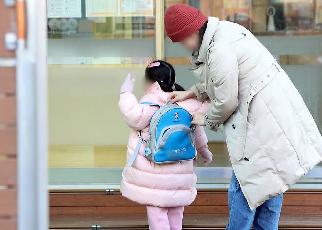 A parent and child are seen at a daycare center in Seoul on Feb. 11. [NEWS1]