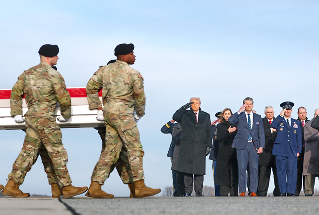 미국의 도널드 트럼프 대통령이 2025년 12월 17일(현지시간) 미국 델라웨어주 도버의 도버 공군기지에서 시리아에서 숨진 아이오와주 방위군 소속 에드가 토레스 토바르 상병과 윌리엄 하워드 상병, 그리고 시리아에서 통역사로 활동하던 미시간주 매컴 출신 아야드 만수르 사카트의 유해를 옮기는 장엄한 송환식(dignified transfer) 도중, 군인들이 운구함을 옮기는 모습을 향해 거수경례하고 있다. [사진 = 로이터 연합뉴스]