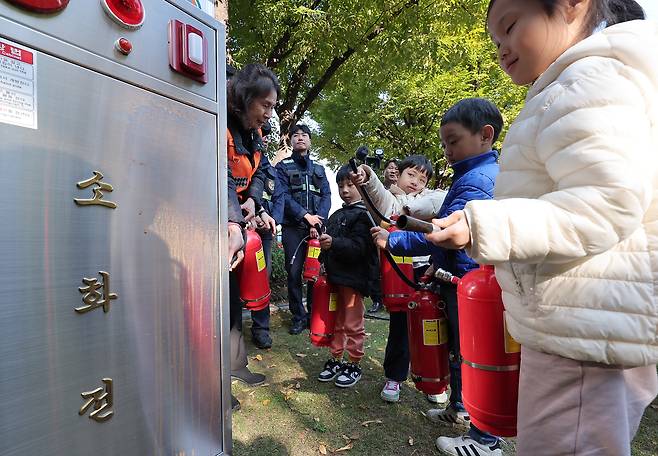 서울 종로구 정부서울청사에서 가을·겨울철 화재 대비 재난 예방과 대응을 위해 진행된 민방위 훈련에서 어린이집 아동들이 소화기 사용법을 체험하고 있다. /뉴스1