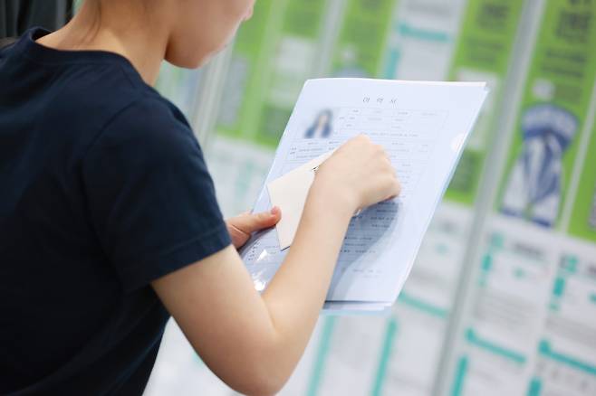 A job seeker holds up a resume, which includes a photo on the top left, at the 2025 Gangnam Job Fair at Coex in Gangnam District, southern Seoul, on June 5. [YONHAP]
